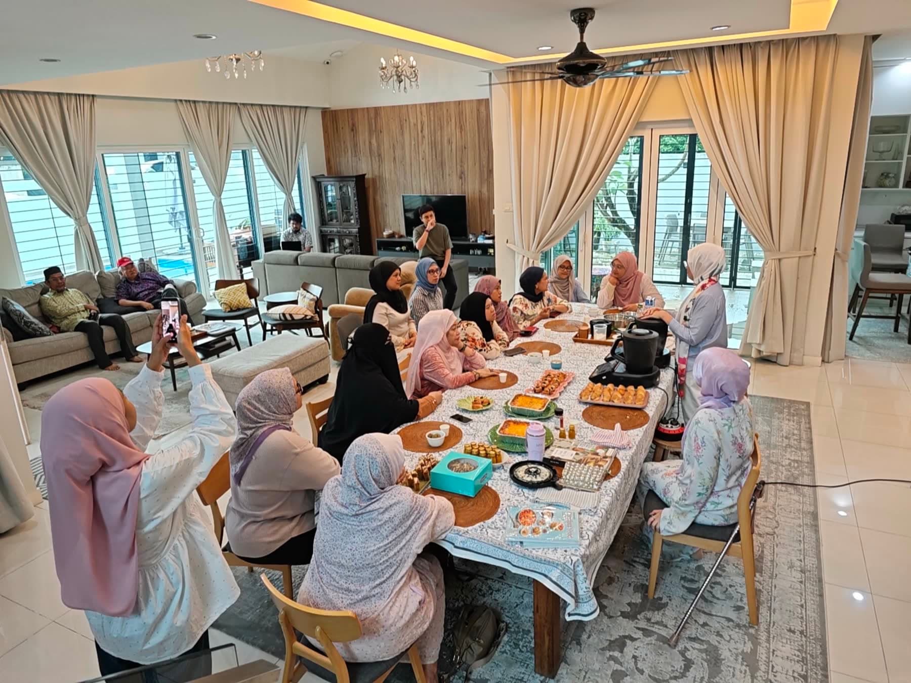 CooknShare members around a long table watching a cooking demo at a community session