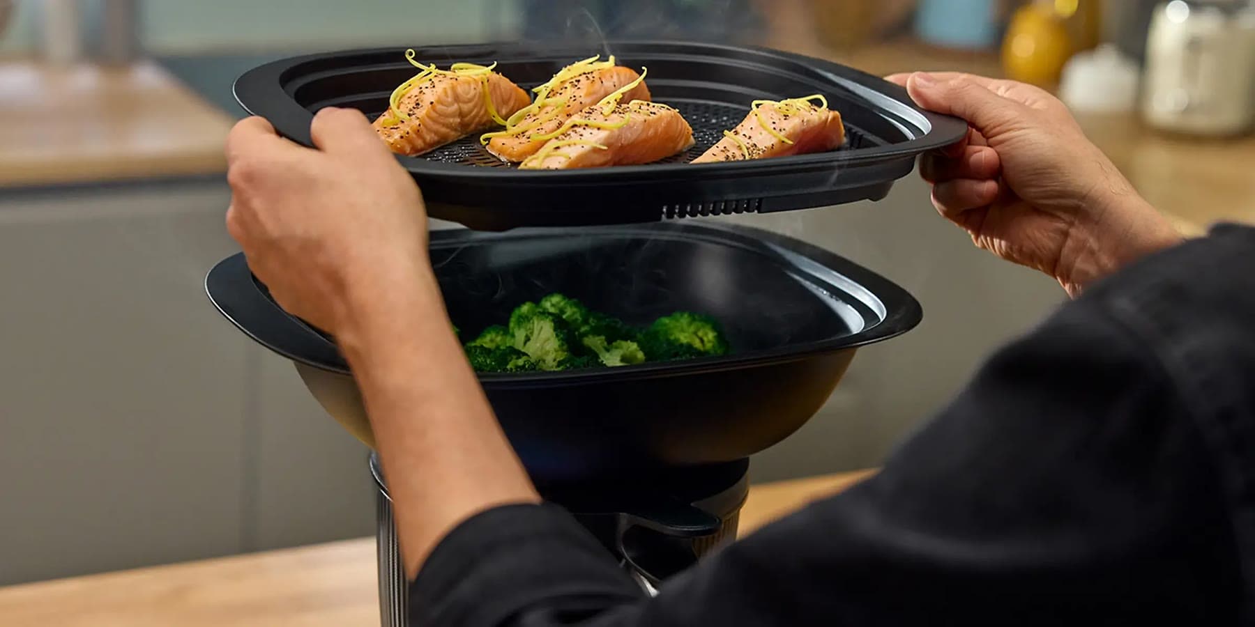Lifting a Varoma tray of steamed salmon above a tier of broccoli on the Thermomix®