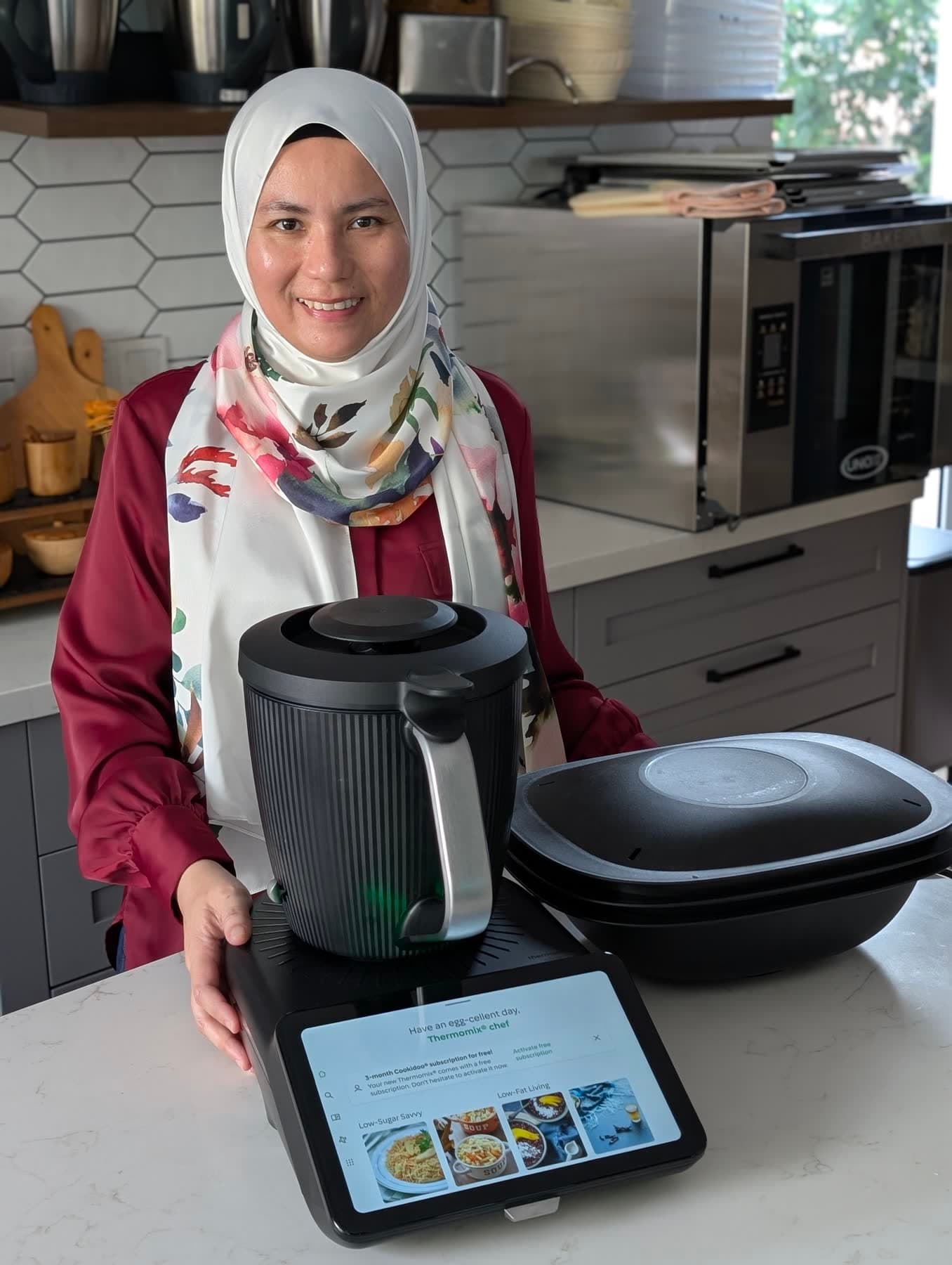 Kartini smiling behind a Thermomix® TM7 and its Varoma dish in a bright kitchen