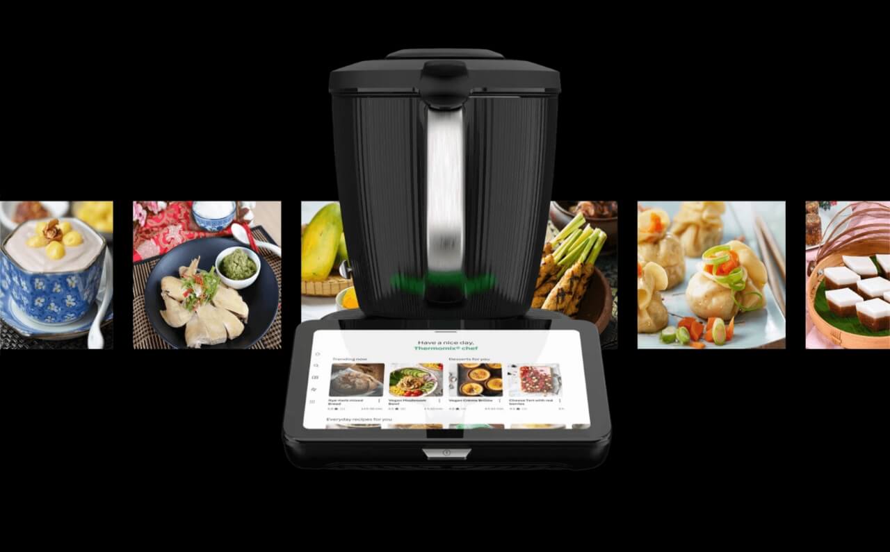 Thermomix 7 with digital recipe slides and prepared meals in the background, ideal for batch cooking and smart meal prep.