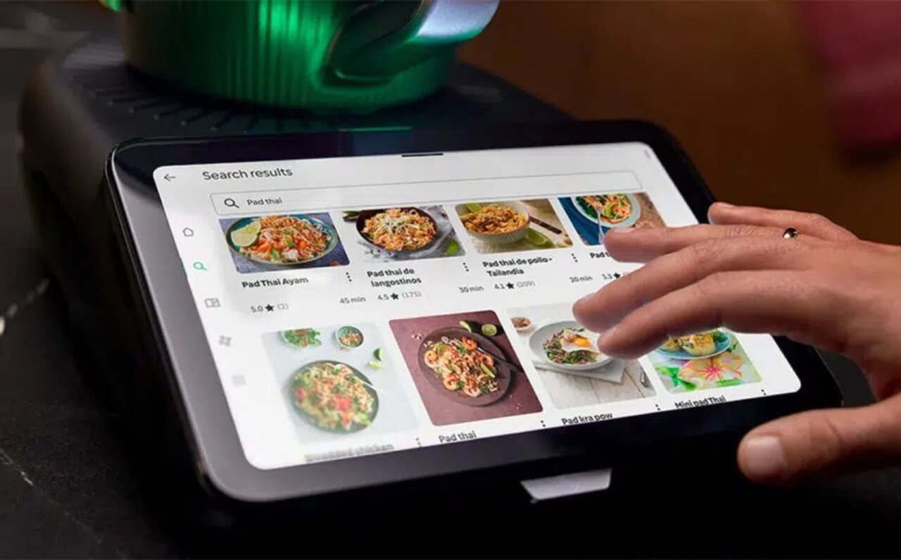 Close-up of a hand navigating the Thermomix 7’s 10-inch multi-touch display, showcasing its user-friendly interface and smart cooking options.